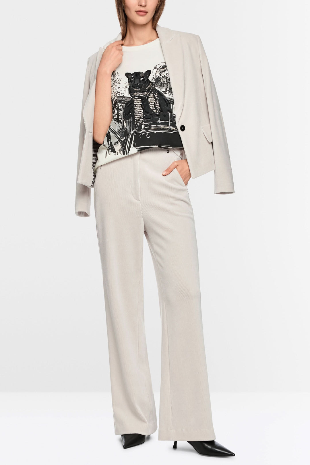 Femme portant un pantalon large en velours côtelé avec blazer chic et tee-shirt imprimé, style moderne et élégant.