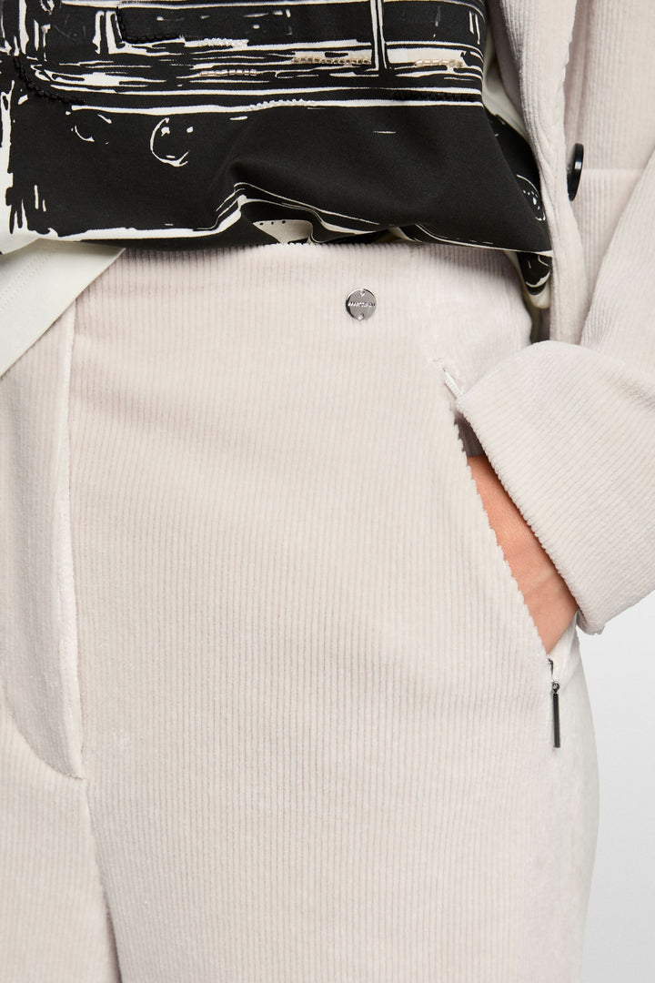 Gros plan sur un pantalon large en velours côtelé beige avec une fermeture éclair, taille mi-haute, élégant et confortable.