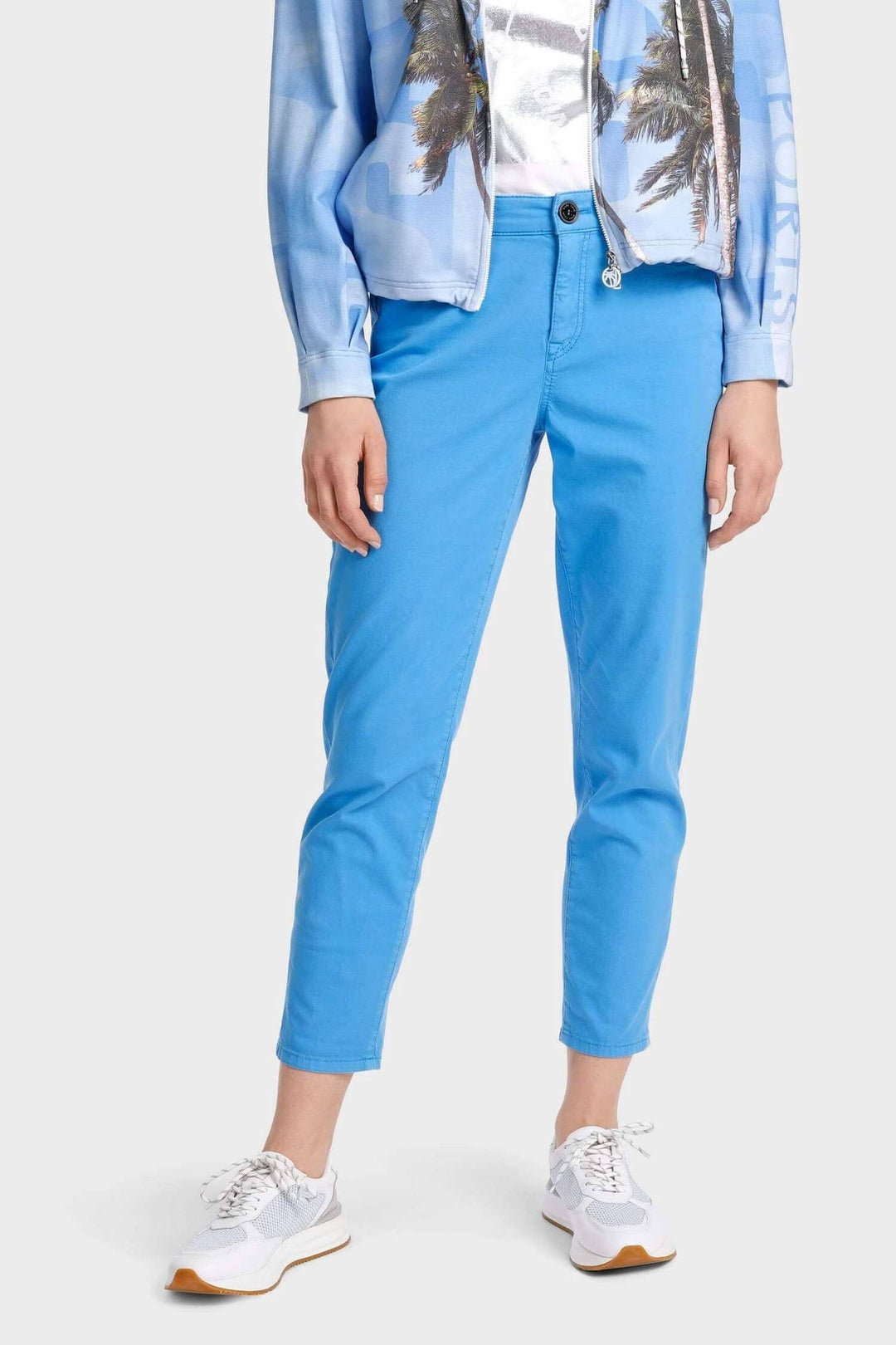 Pantalon décontracté bleu porté avec des baskets blanches et une veste imprimée, parfait pour un look stylé et confortable.