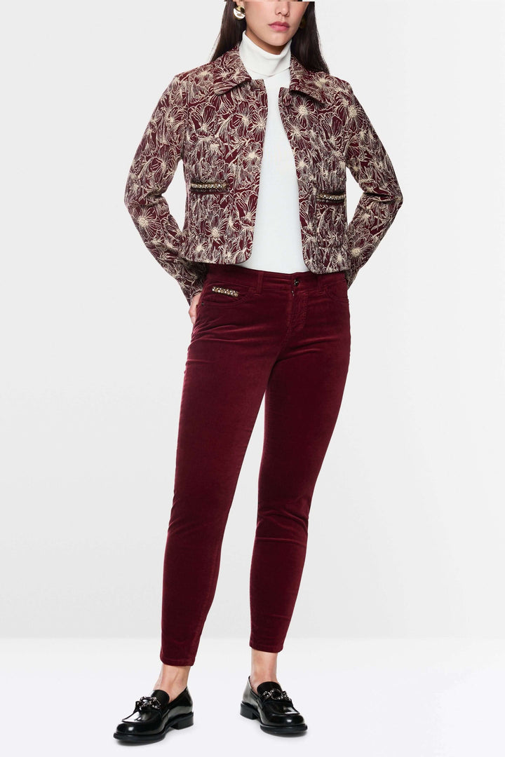 Femme portant un pantalon taille basse en velours rouge avec une veste à motif, style chic et moderne.