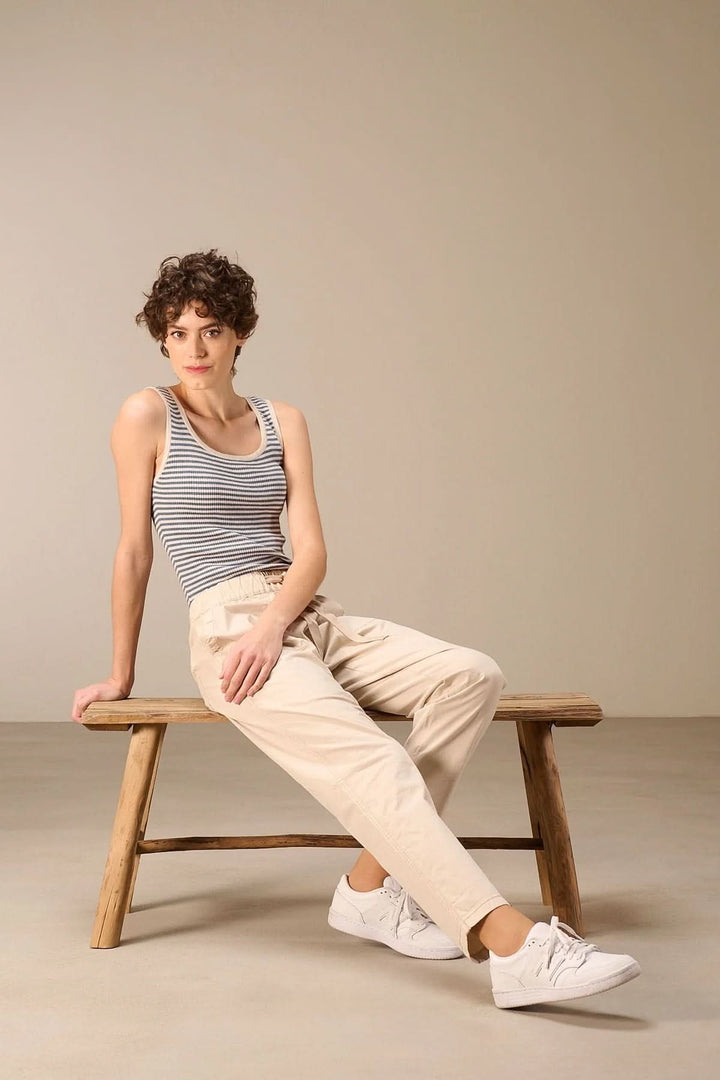 Femme assise portant un pantalon taille élastique beige, style décontracté et moderne avec coupe droite légèrement fuselée.