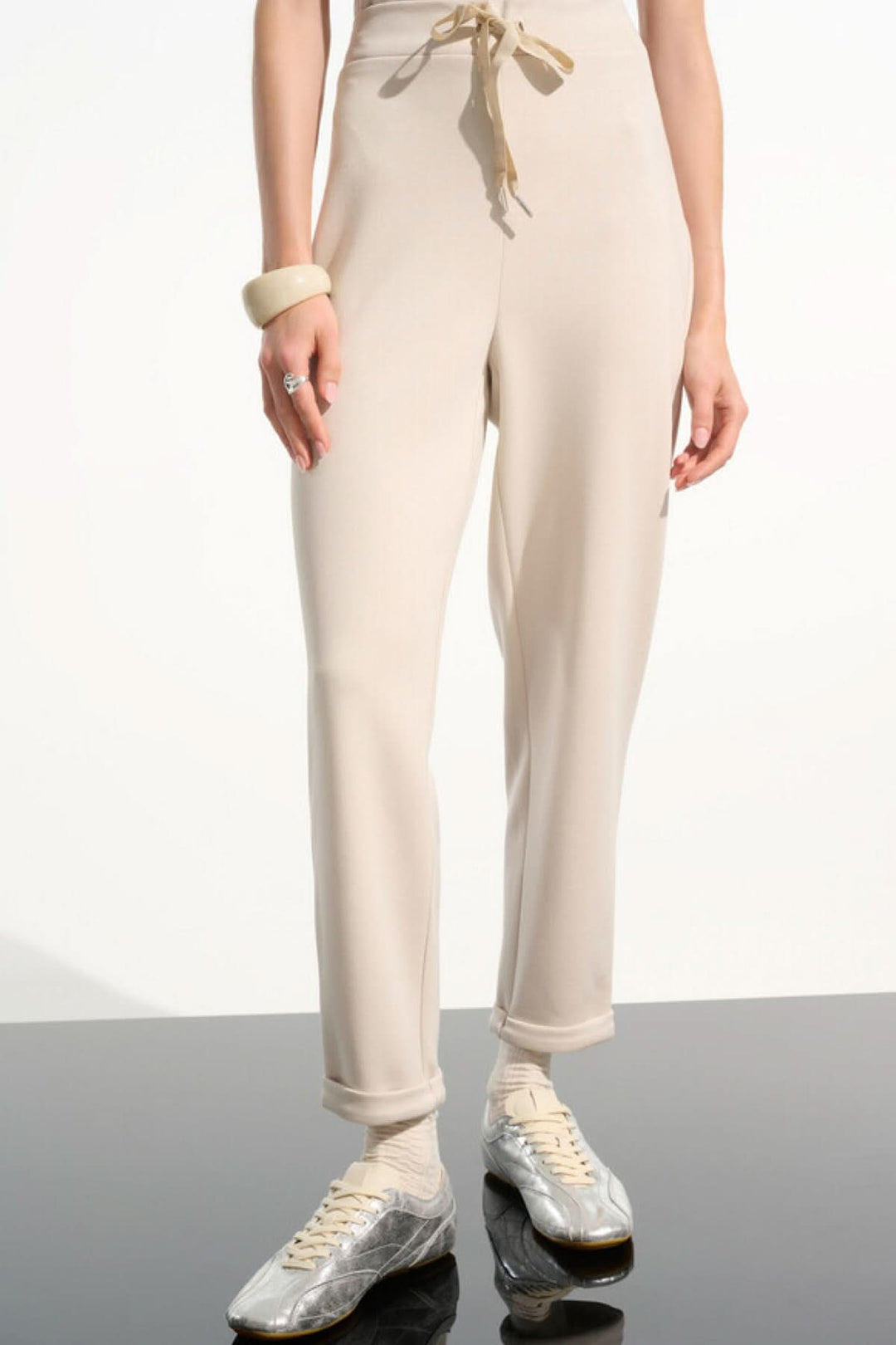Pantalon à taille nouée coupe droite beige avec taille élastique et cordon, idéal pour une tenue moderne et polyvalente.