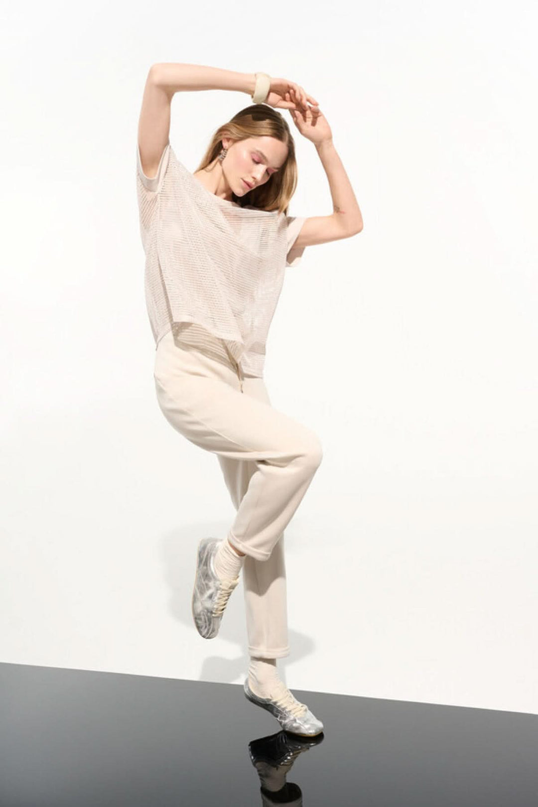 Modèle portant un pantalon à taille nouée coupe droite avec t-shirt beige et baskets, silhouette moderne et épurée sur fond blanc.