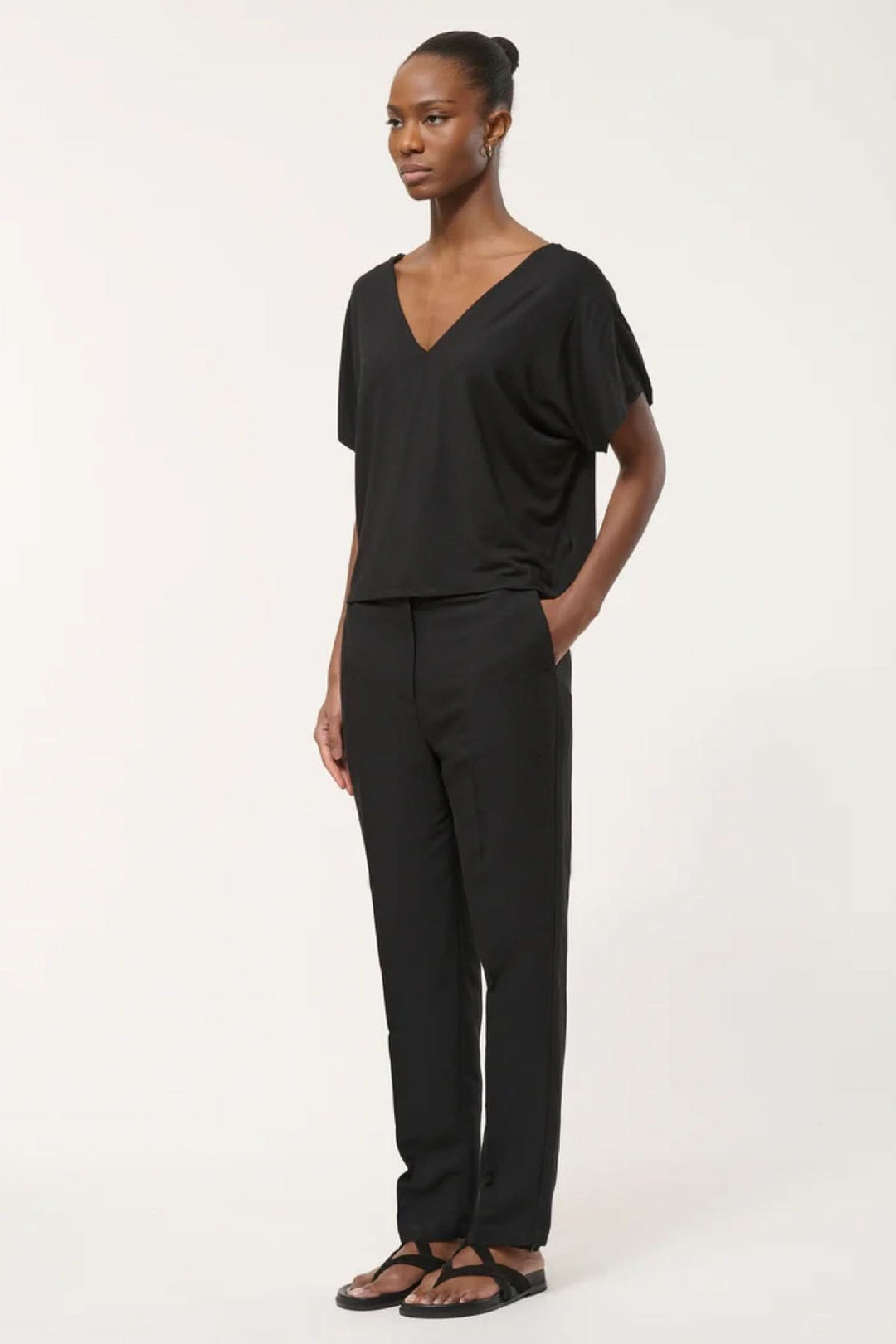 Femme portant un pantalon tailleur coupe droite noir, style élégant, adapté pour le bureau ou une tenue habillée.