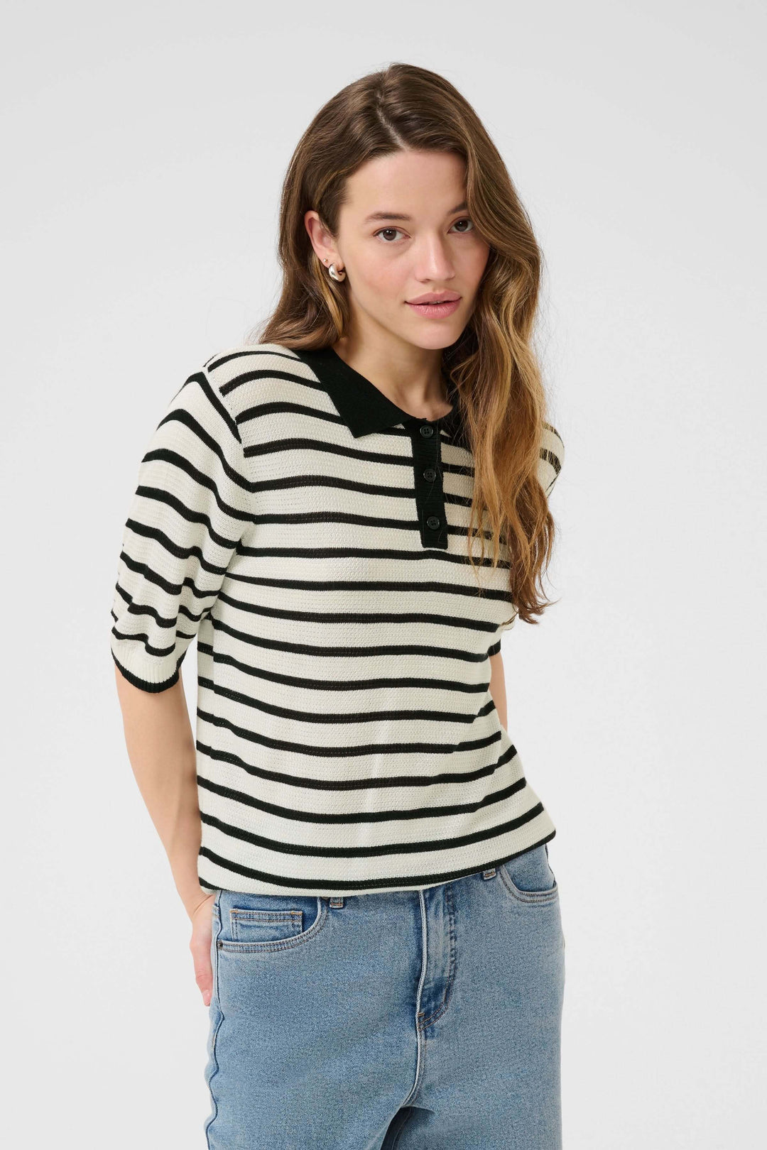 Polo Amalia en maille rayée, col contrastant, style rétro-chic avec coupe moderne, porté avec un jean.