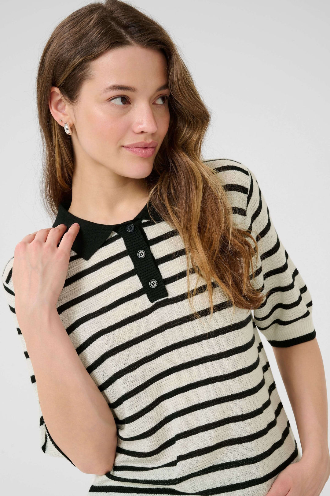 Femme portant un polo en maille rayée au style rétro-chic avec col contrastant et patte de boutonnage.