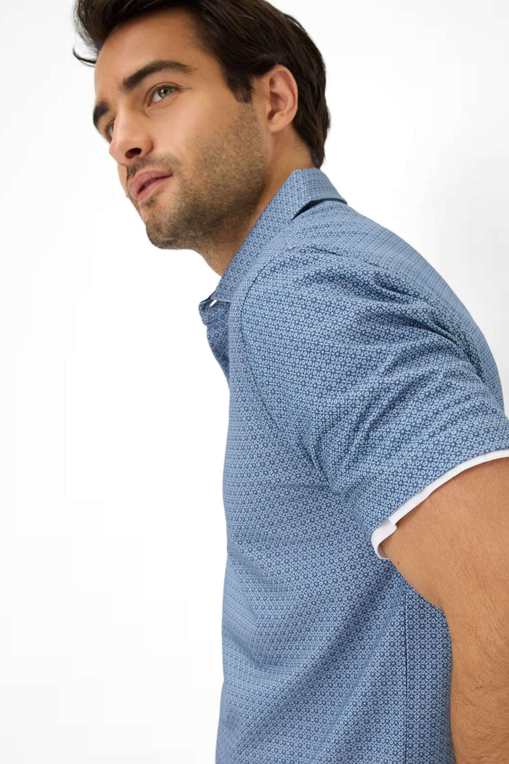 Homme portant un polo à manches courtes avec motif géométrique, décontracté et élégant.