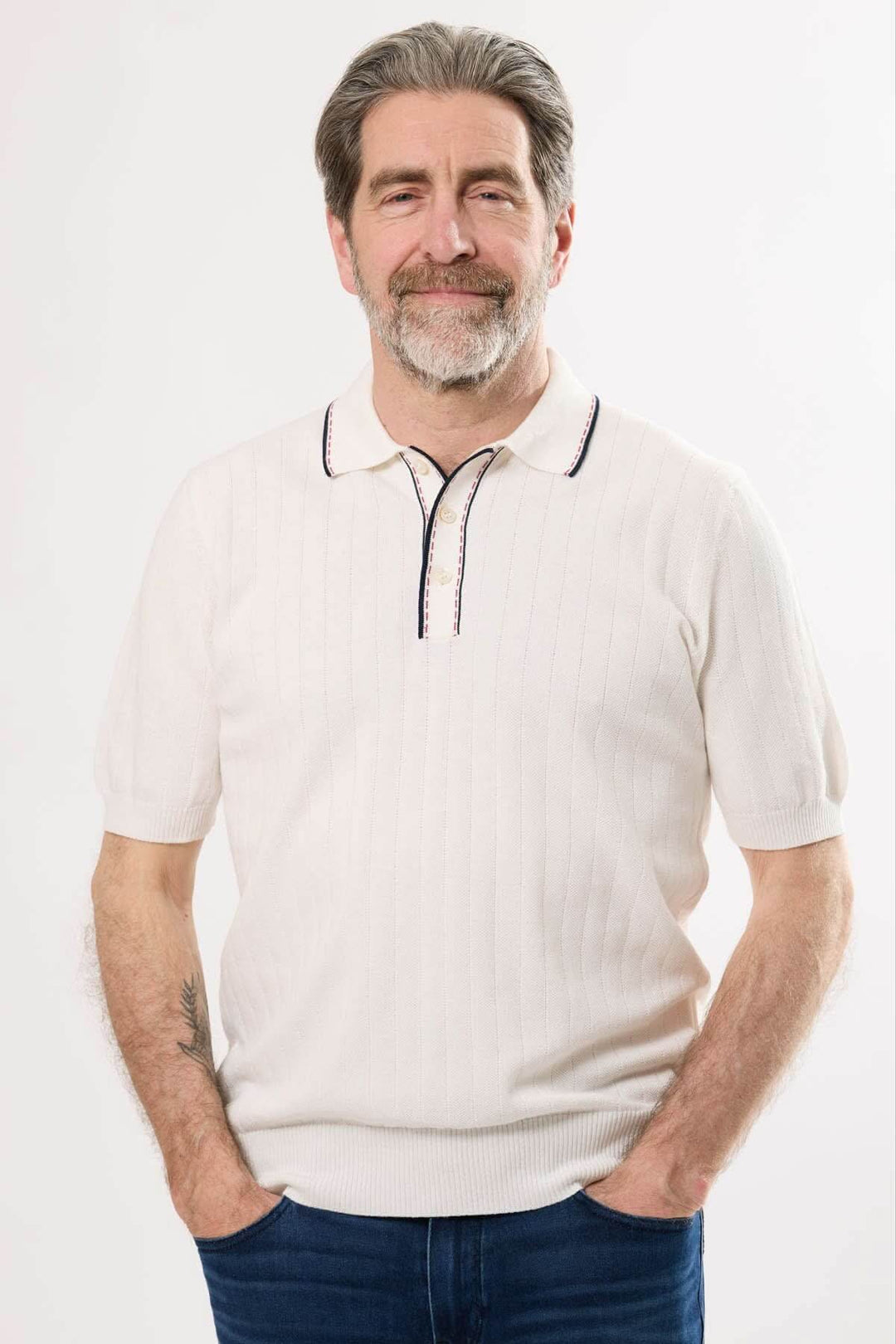 Homme portant un polo en tricot beige avec col contrastant, idéal pour un look rétro-chic.