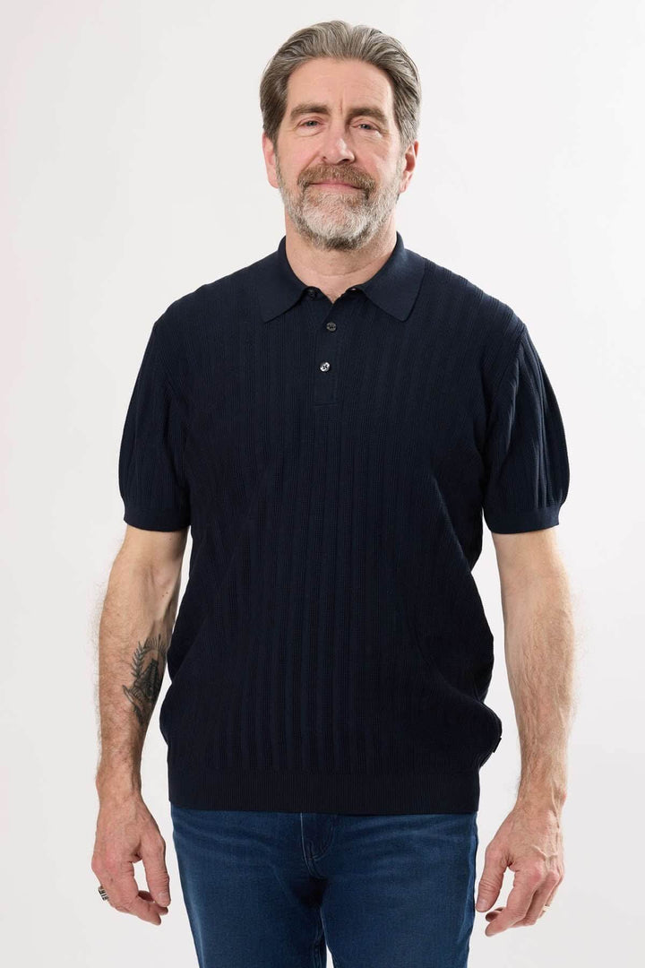 Homme portant un polo en tricot structuré avec motif côtelé vertical, idéal pour un style raffiné.