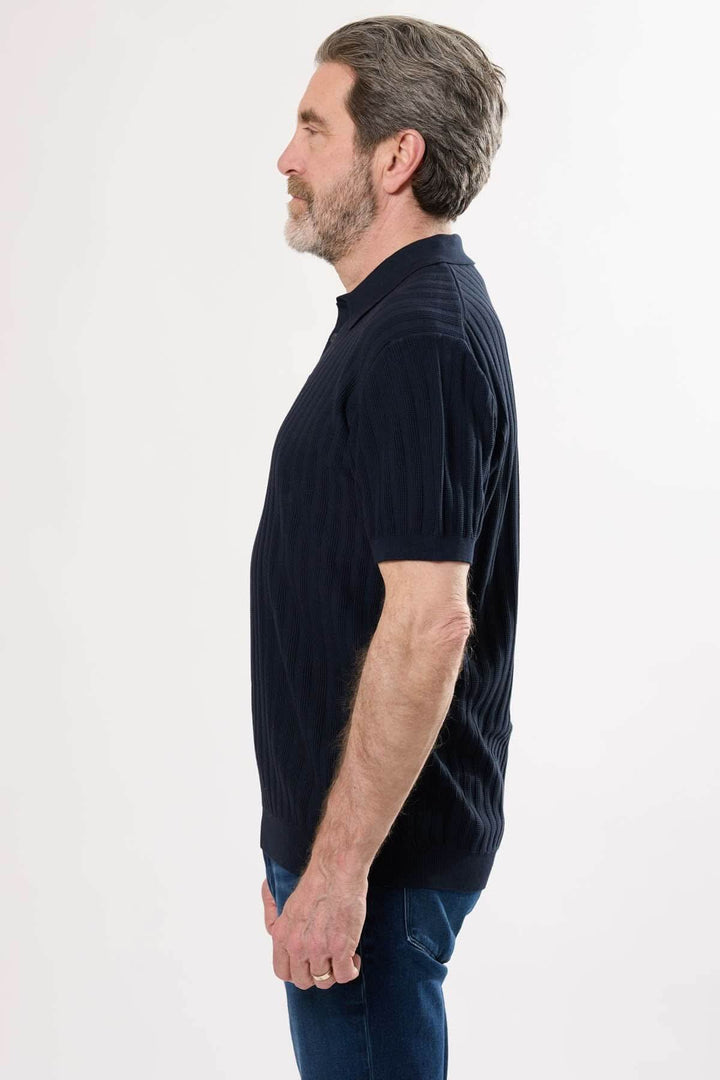 Homme portant un polo en tricot côtelé vertical, silhouette rétro-chic, col classique, vue de profil.