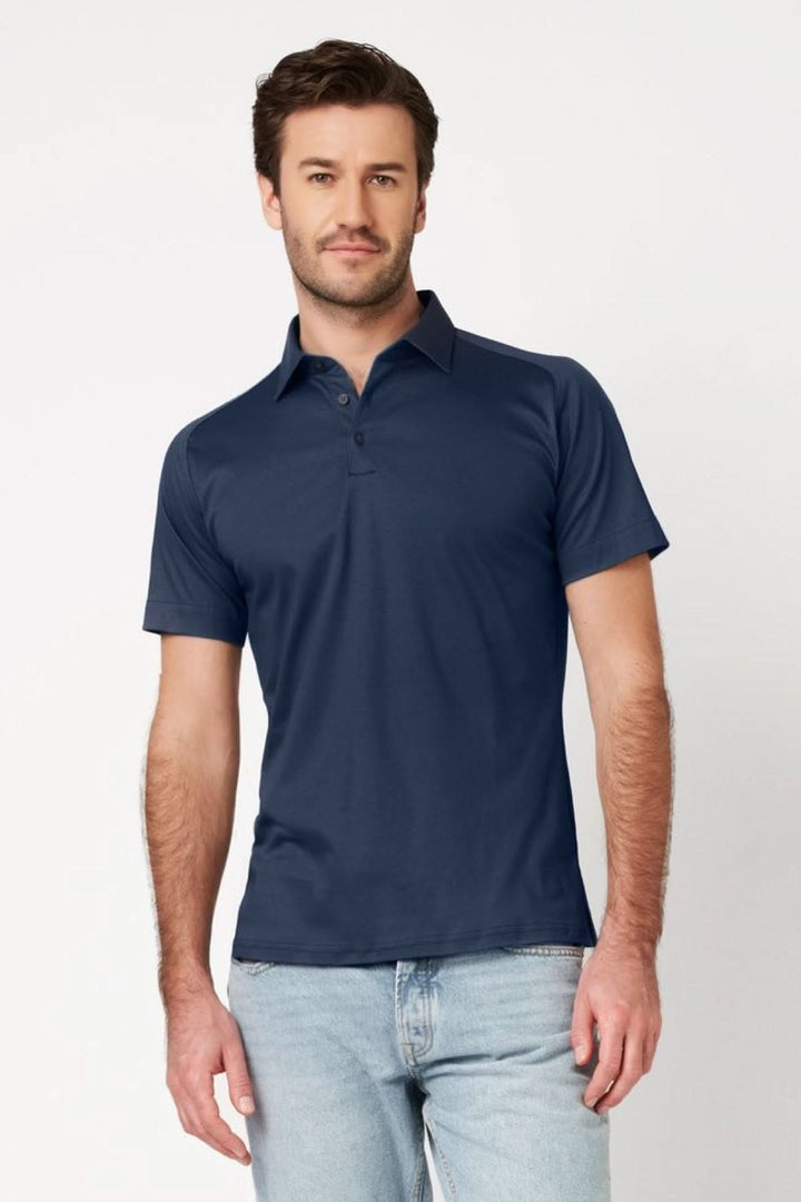 Homme portant un polo manches courtes performance épuré de couleur bleue, coupe ajustée, idéal pour un look polyvalent et moderne.