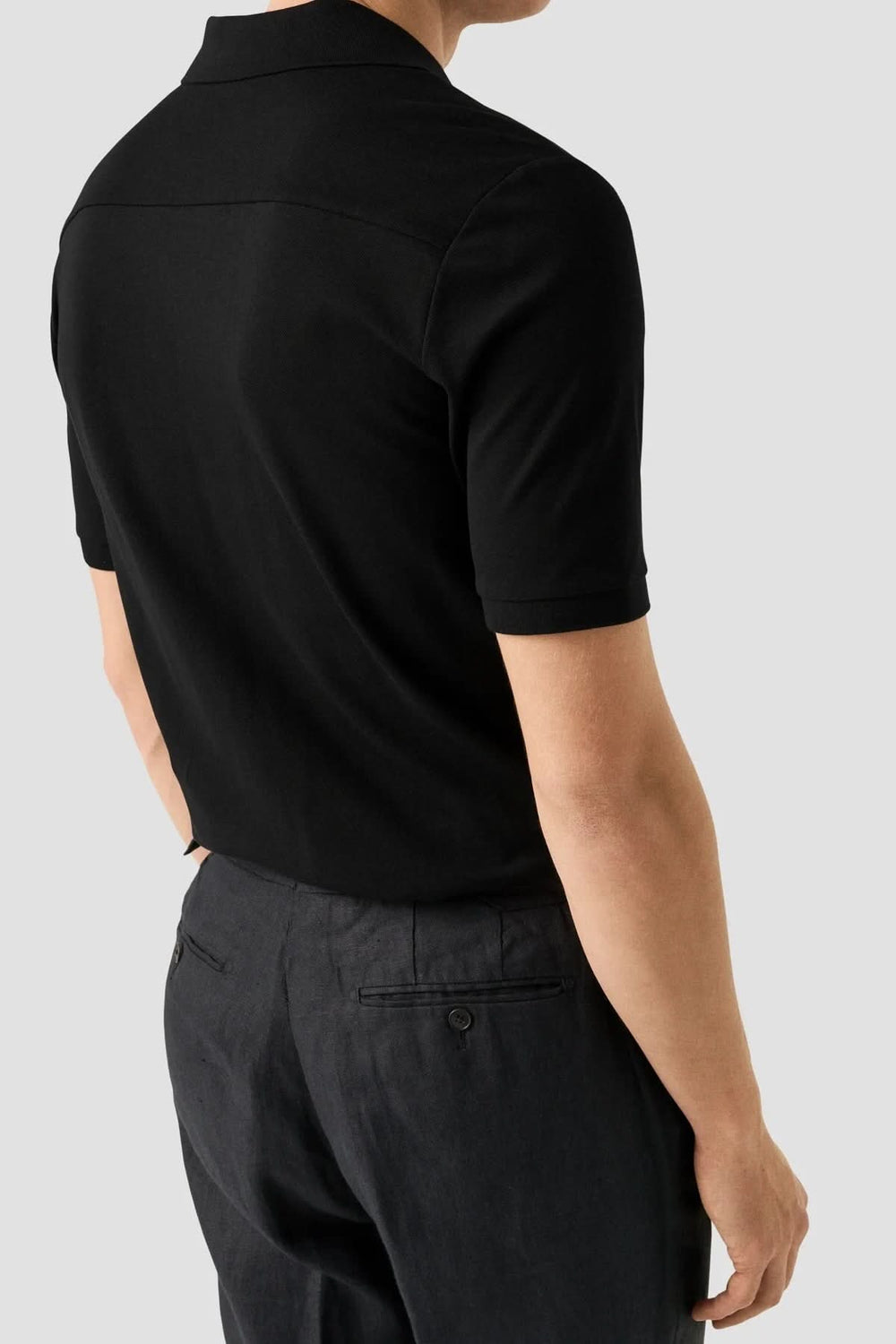 Homme portant un polo piqué à manches courtes, coupe ajustée et moderne, allure épurée pour un look polyvalent et soigné.
