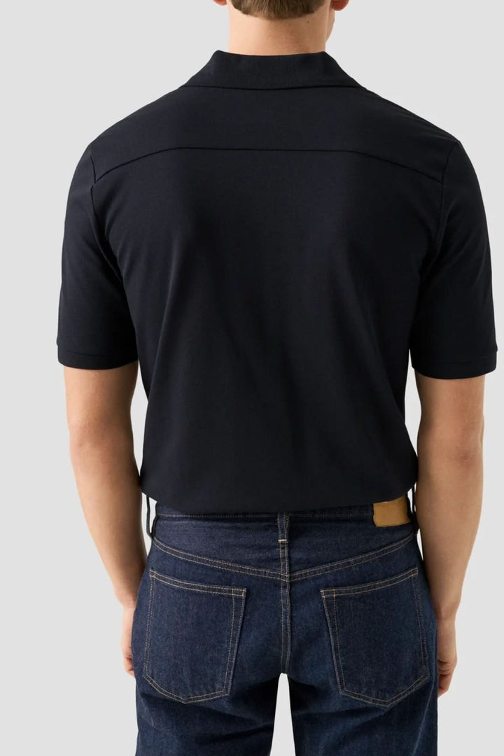 Homme portant un polo piqué à manches courtes moderne noir, vue de dos, col structuré et coupe ajustée, mode polyvalente et décontractée.