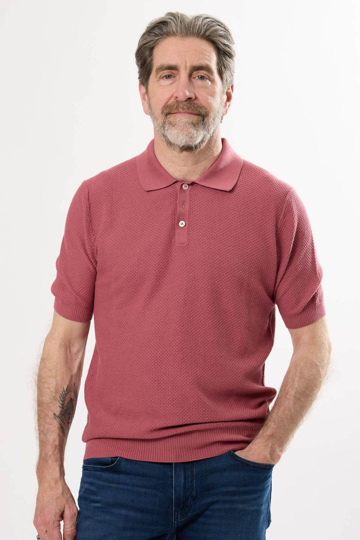 Polo raffiné rose en maille texturée, homme en tenue décontractée chic, col structuré à boutons.