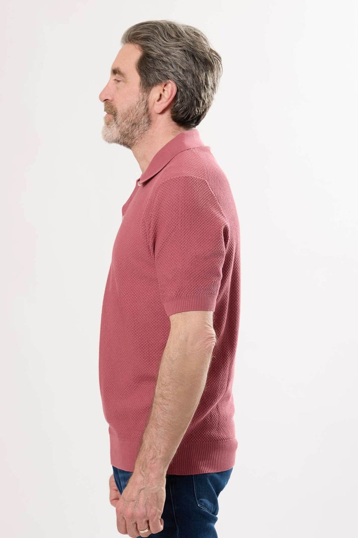 Polo raffiné en maille texturée, col structuré, coupe ajustée, porté par un homme de profil.