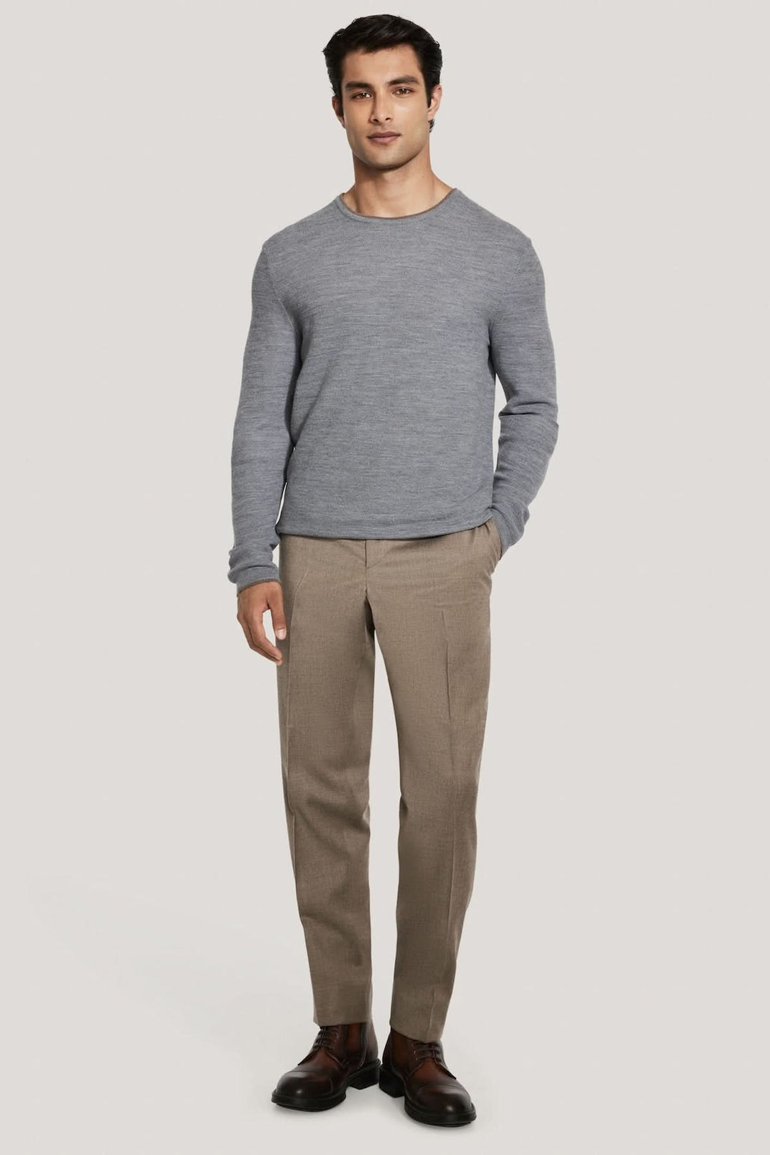 Homme portant le Pull col ras du cou Belvedere en laine gris, idéal pour une allure moderne et confortable sous une veste sur mesure.