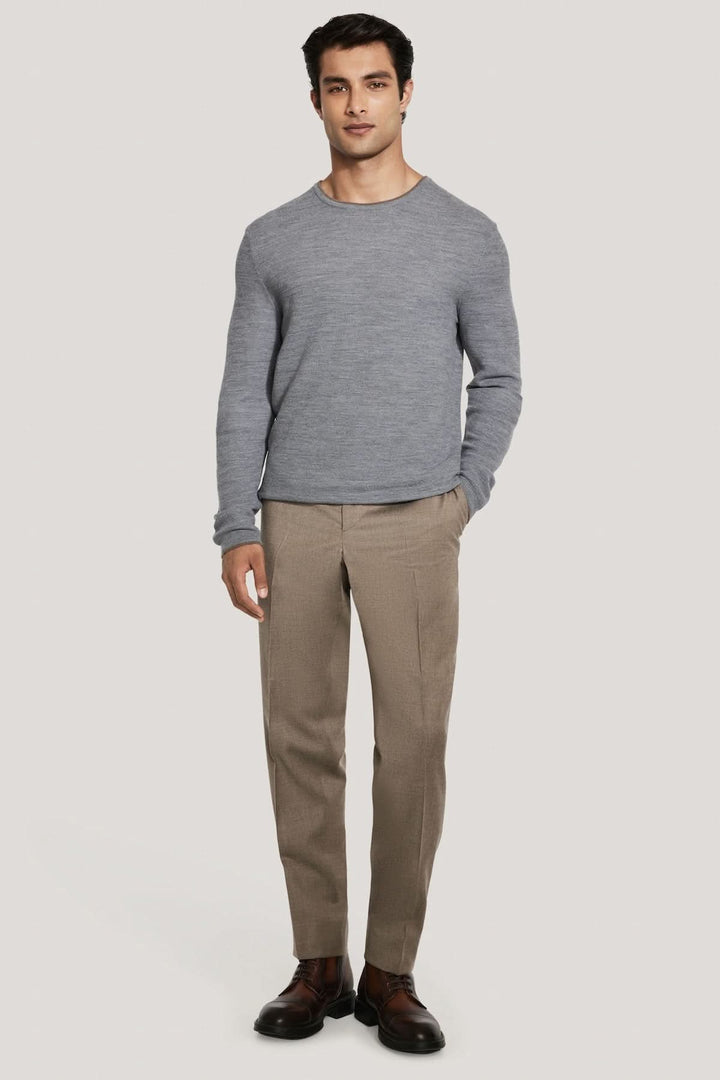 Homme portant le Pull col ras du cou Belvedere en laine gris, idéal pour une allure moderne et confortable sous une veste sur mesure.