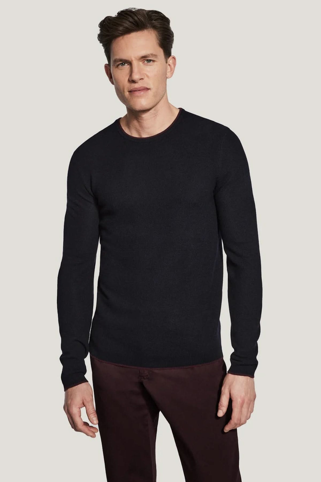 Homme portant un Pull col ras du cou Belvedere en laine noire, élégant et polyvalent sous une veste, confort raffiné et coupe soignée.