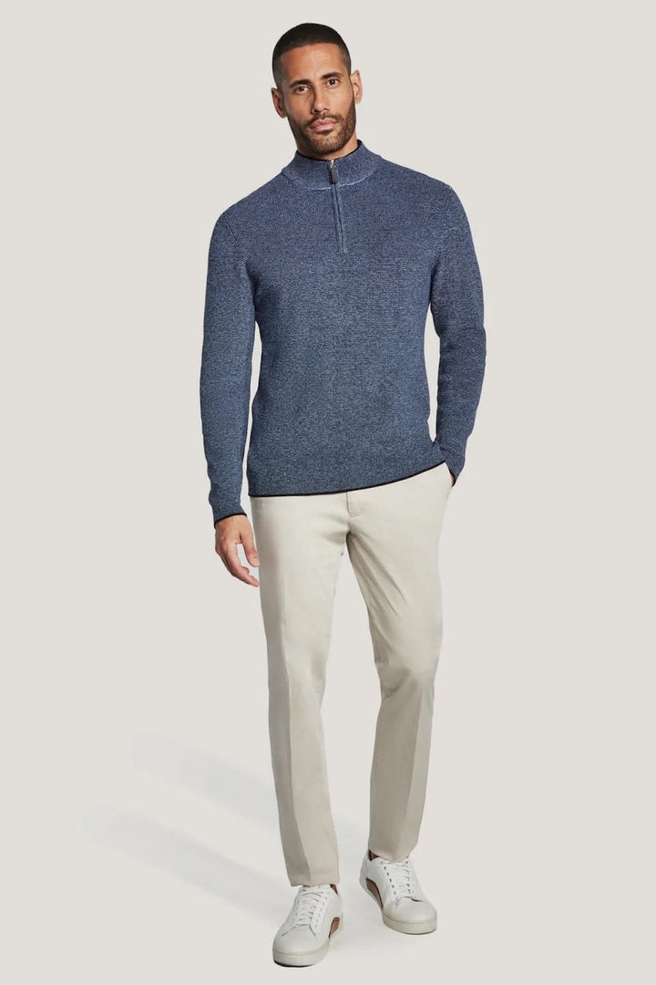 Homme portant un pull quart de zip en coton texturé bleu, avec un pantalon beige, style moderne et épuré.