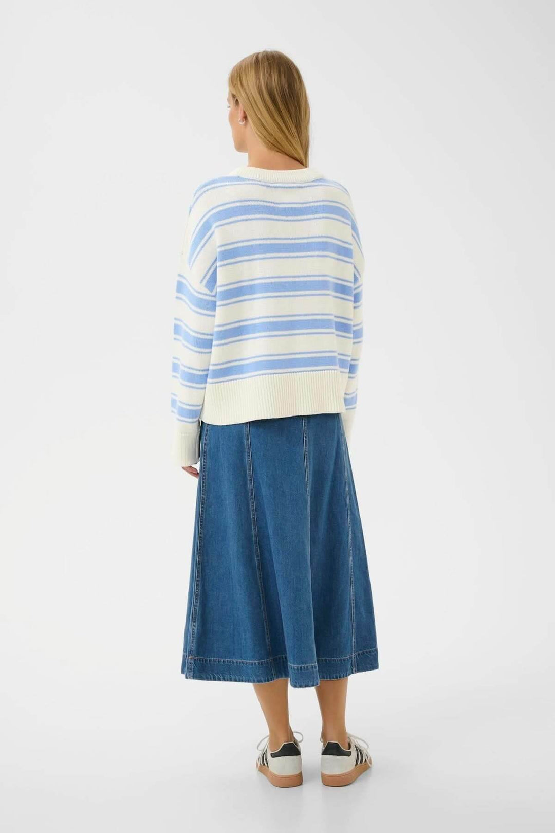 Pull à rayures Serafine avec rayures bleues et blanches, coupe droite et ample, porté avec une jupe en jean pour un style décontracté.