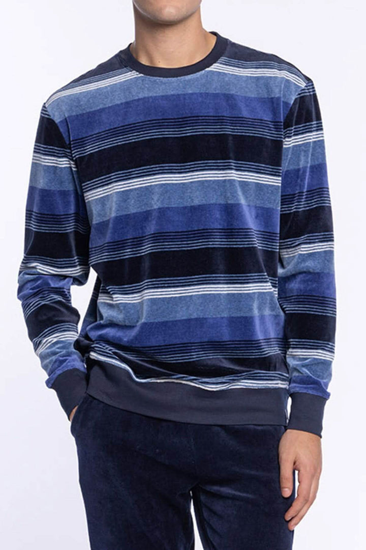 Homme portant un Pyjama Long en Velours de Coton à Rayures, haut bleu à manches longues et pantalon uni, confort et douceur hivernaux.