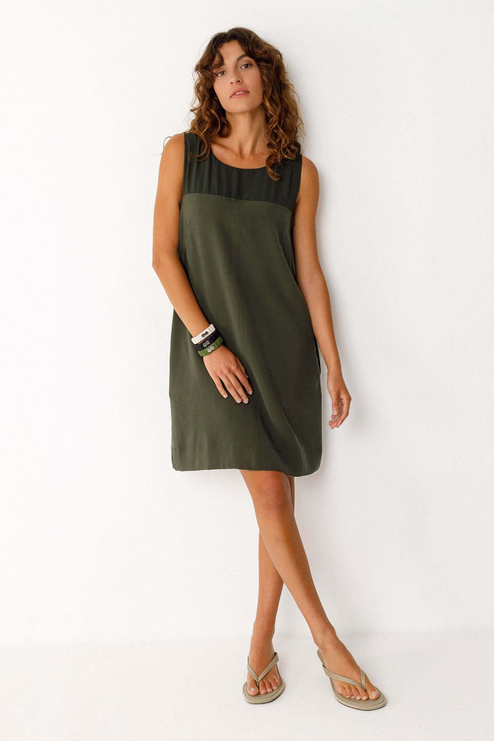 Femme portant une Robe Adara courte fluide sans manches col rond verte, style minimaliste et élégant, idéale pour toutes occasions.