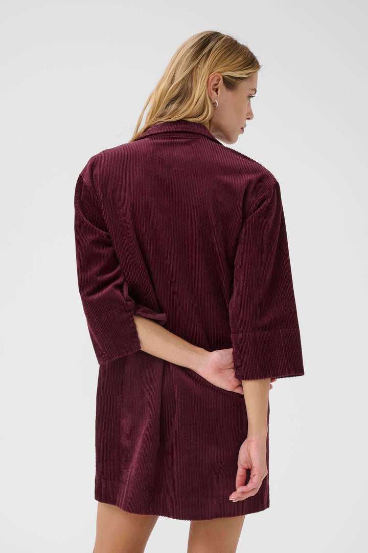 Femme portant la Robe Sharri en velours côtelé avec manches trois-quarts, vue arrière, élégante et décontractée-chic.
