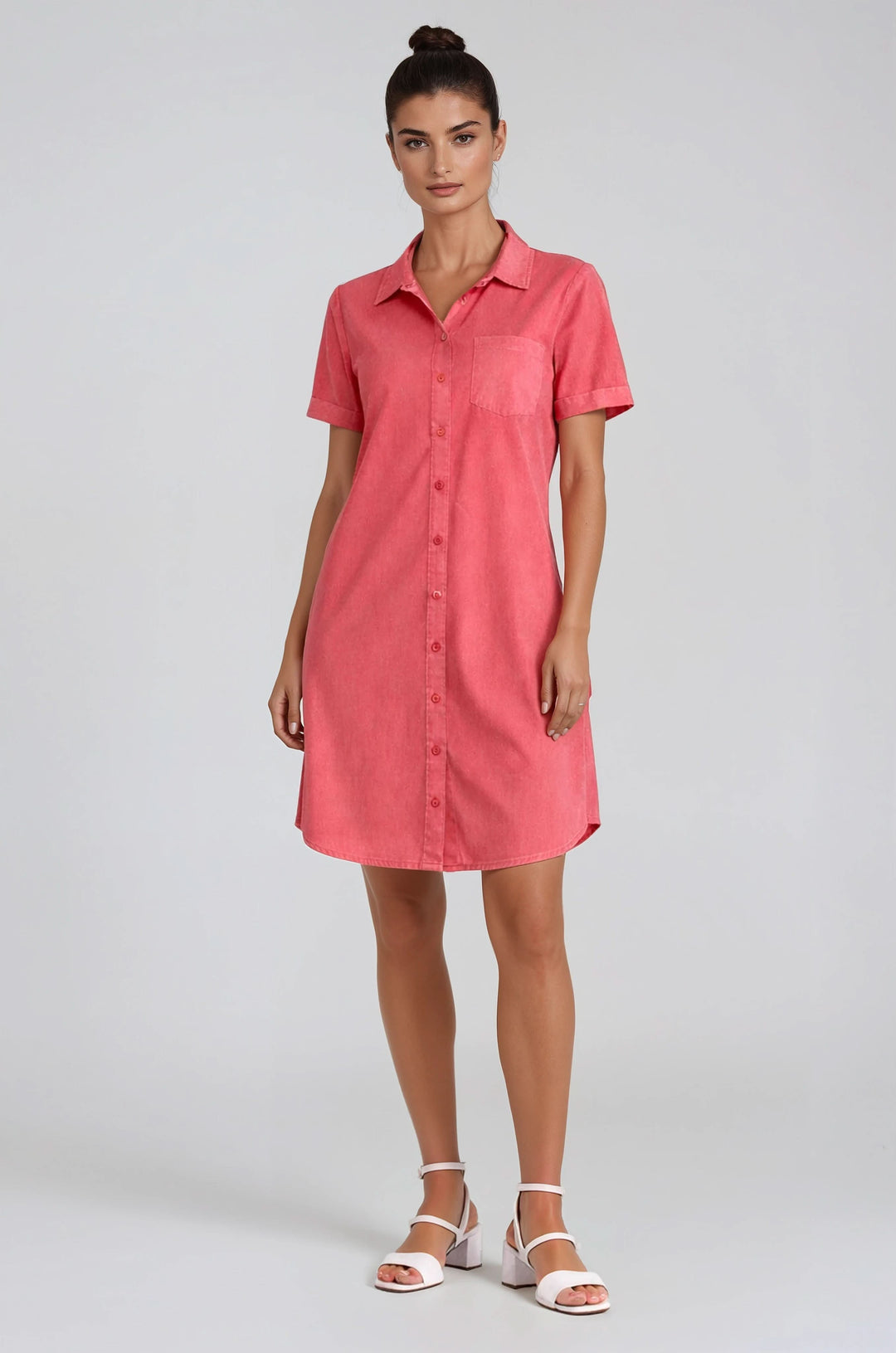 Femme portant une robe chemise à manches courtes boutonnée, coupe droite et légère, style structuré et décontracté, couleur rose.