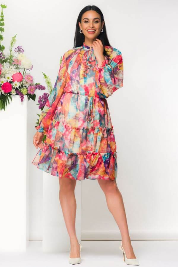 Robe courte fluide imprimée volants col noué avec fleurs en arrière-plan, manches longues et taille ajustable.