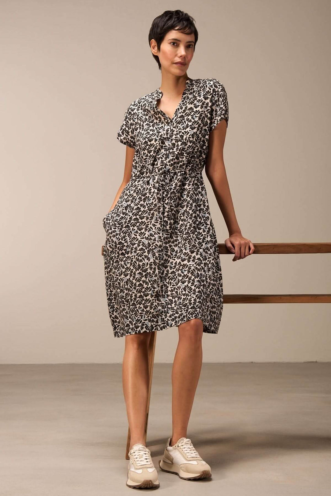 Robe imprimée à taille ajustable, manches courtes, encolure en V, portée avec des baskets.