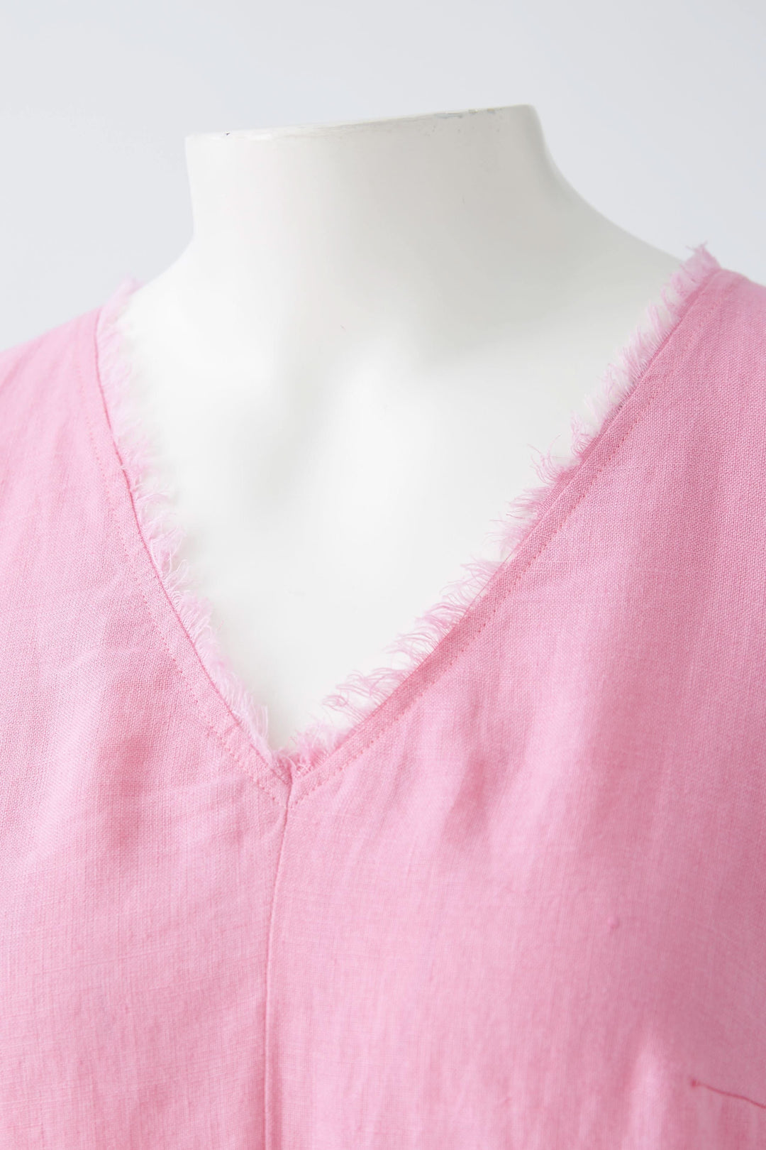 Robe longue en lin rose avec encolure en V et finitions effilochées, parfaite pour journées chaudes.