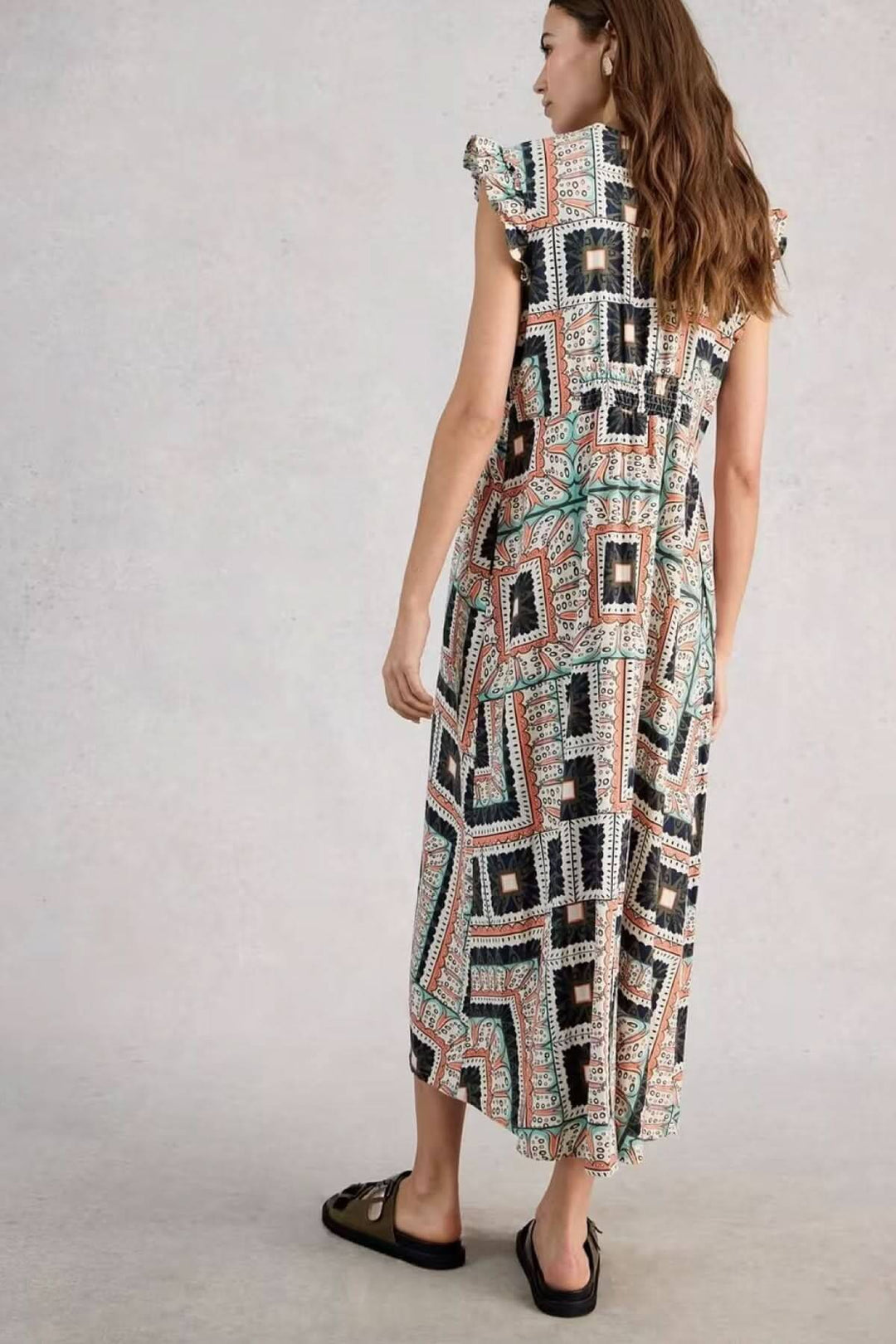 Femme portant une robe longue sans manches Lorna en lin mélangé avec imprimé graphique et coupe fluide tournée de dos.