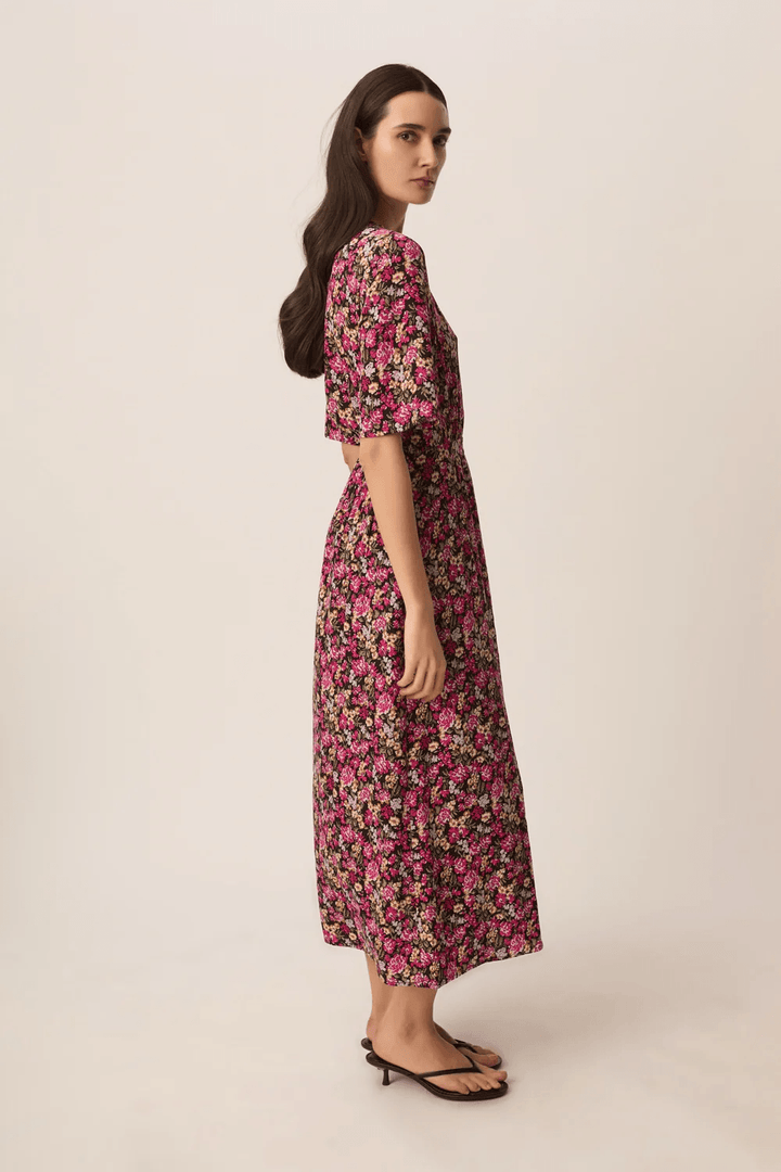 Modèle portant une Robe midi Elaly portefeuille à manches fluides avec motif floral, vue latérale montrant la coupe fluide et élégante.