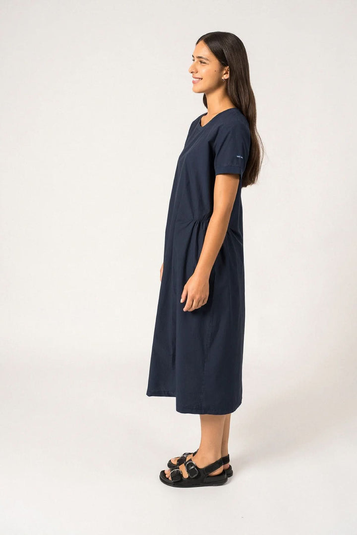 Femme portant la robe midi Morgane avec coupe droite et manches courtes, montrant la polyvalence du style quotidien élégant.