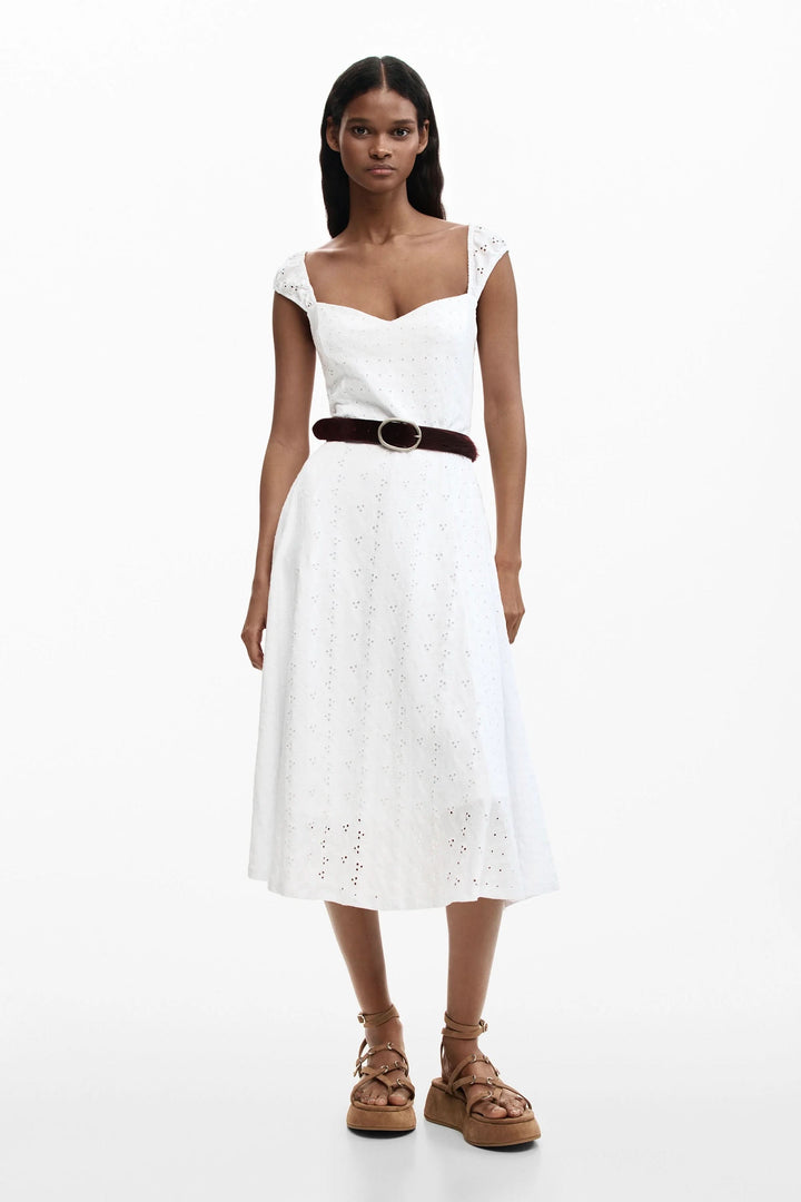 Femme portant une robe midi brodée en broderie anglaise avec des bretelles larges et une encolure cœur, silhouette mise en valeur.