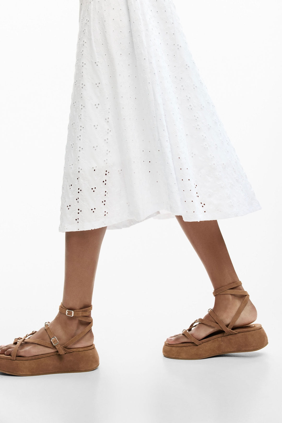 Robe midi brodée en broderie anglaise blanche avec jupe évasée fluide et sandales en cuir marron.