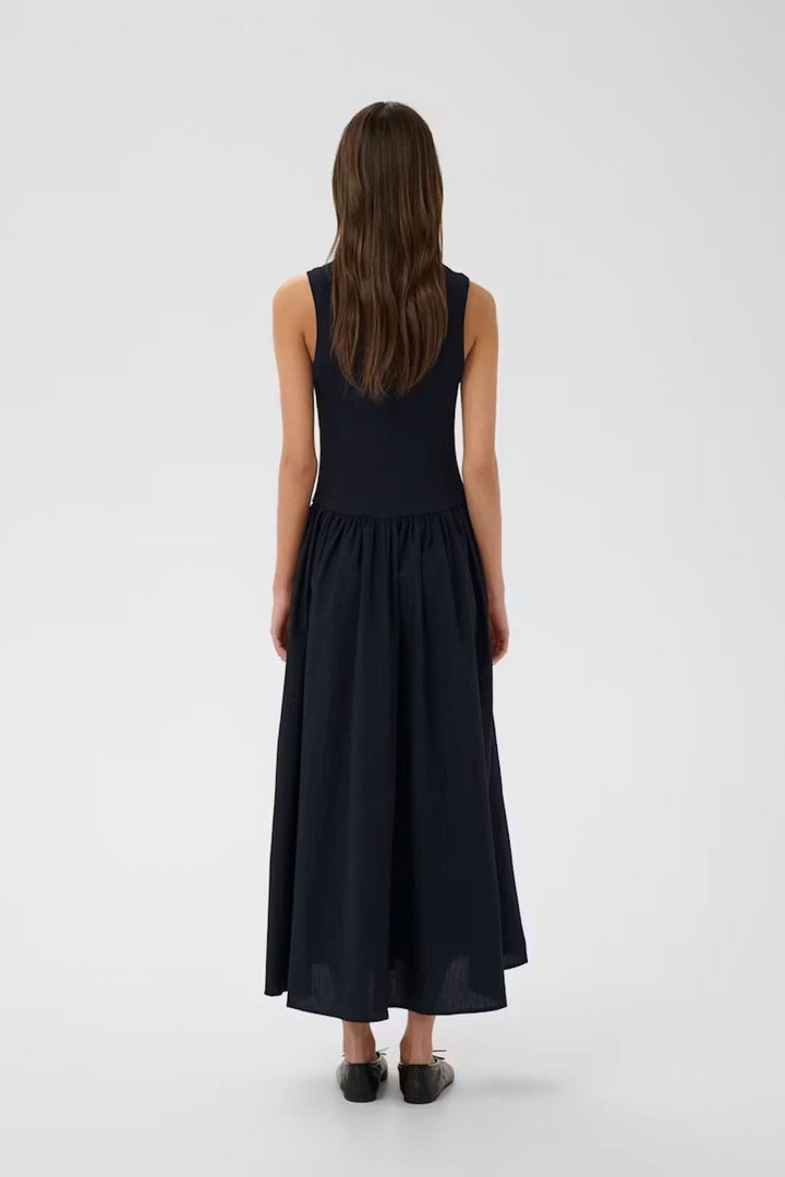 Vue arrière de la robe midi sans manches Dagnama avec jupe ample et haut ajusté, portée par un mannequin féminin sur fond neutre.