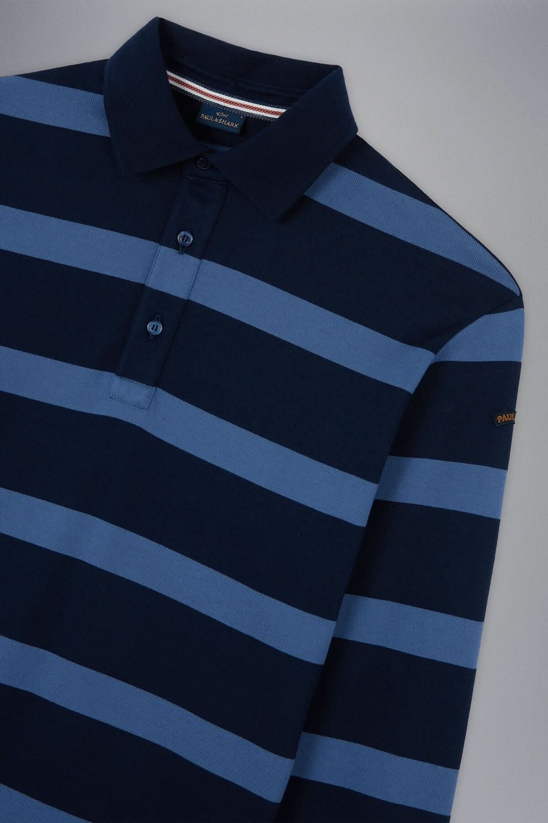 Polo rayé bleu marine et bleu clair avec col classique, idéal pour un style décontracté et sophistiqué.