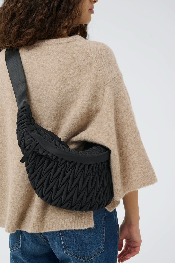 Sac bandoulière matelassé Samy Bumbag porté par une femme, design moderne avec texture froncée, idéal pour un style urbain.