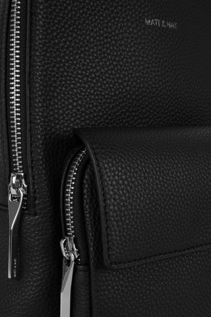 Détail du sac à dos Allar montrant les fermetures éclair et le cuir texturé en noir.