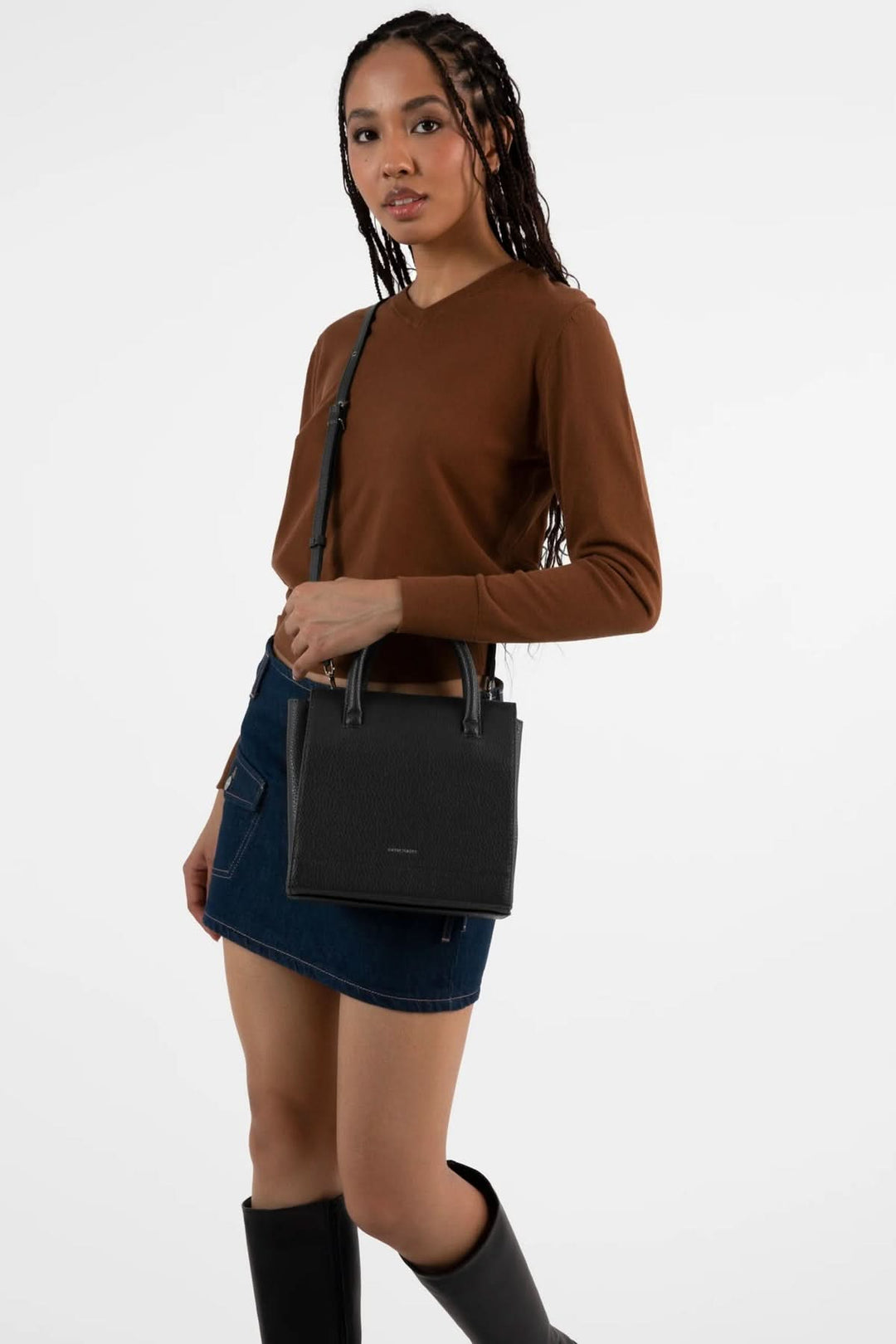 Femme portant un sac à main Adelsm noir, style élégant avec double poignée, associé à une jupe en denim.