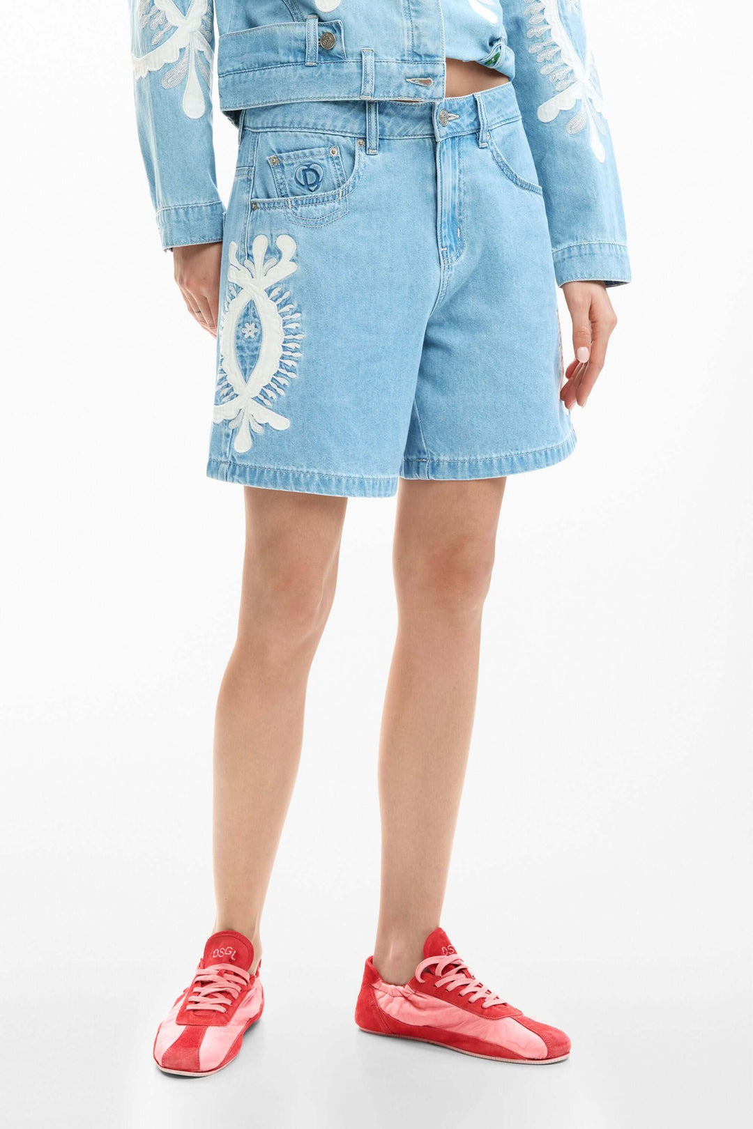 Short en jean brodée avec broderies graphiques et coupe droite, idéal pour un look estival polyvalent.