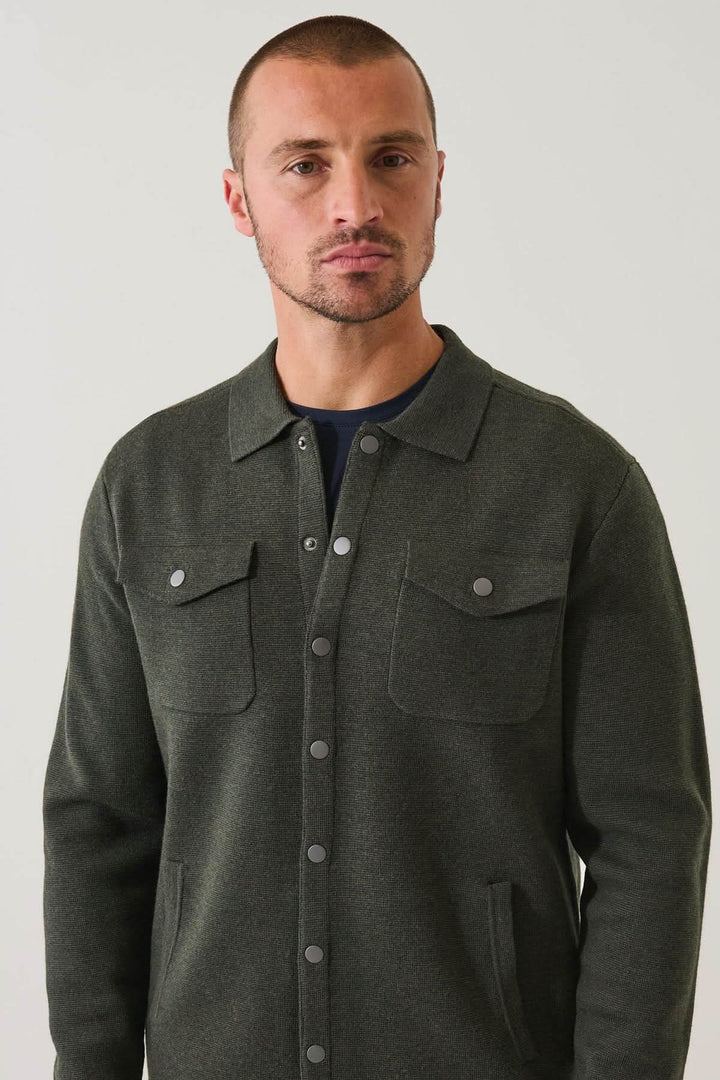 Homme portant une surchemise en laine mérinos extra-fine à boutons-pression, couleur sombre, style élégant et confortable.