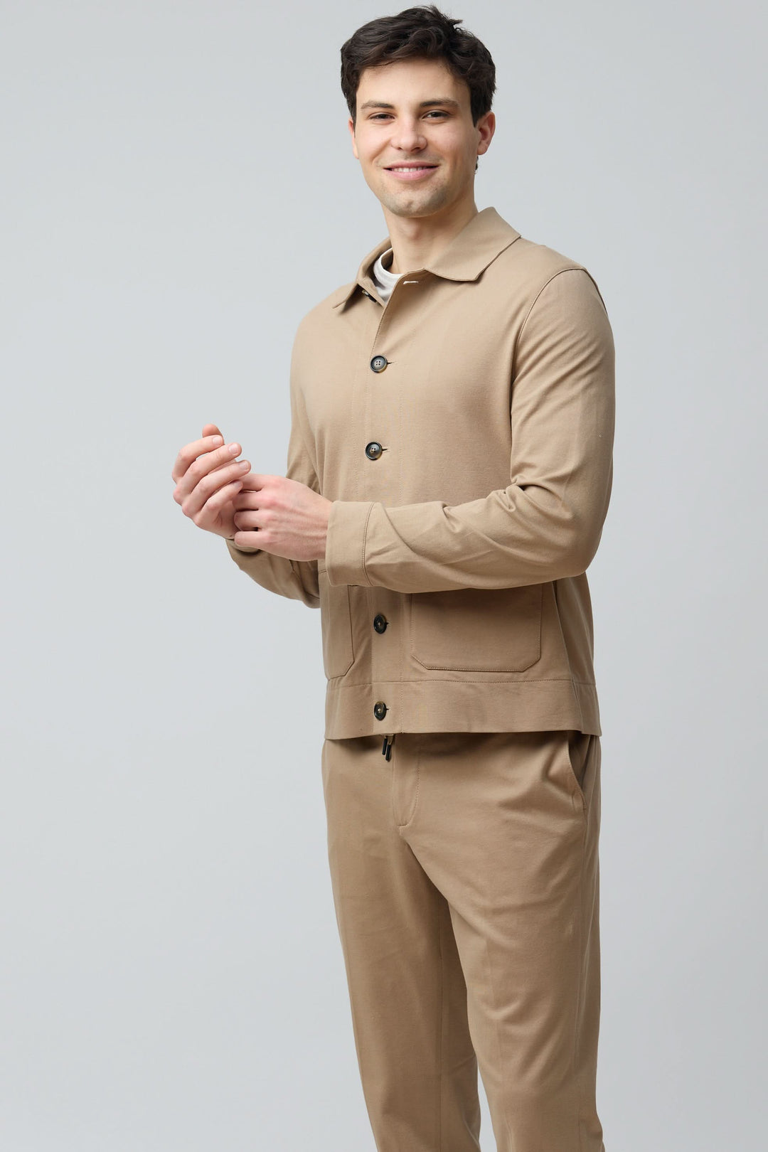 Homme portant une surchemise stretch beige avec col structuré et fermeture boutonnée, tenue décontractée et moderne.