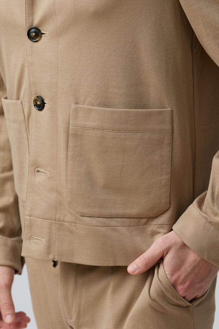 Surchemise stretch beige avec poches et boutons, style moderne et polyvalent, matière souple pour confort et aisance de mouvement.