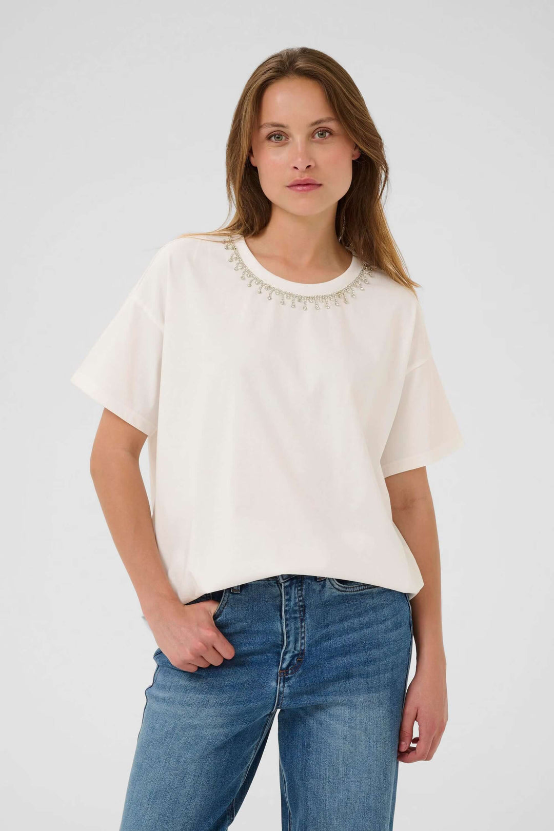 Femme portant le T-shirt Helen blanc à col rond et manches courtes pour un look confortable et polyvalent.