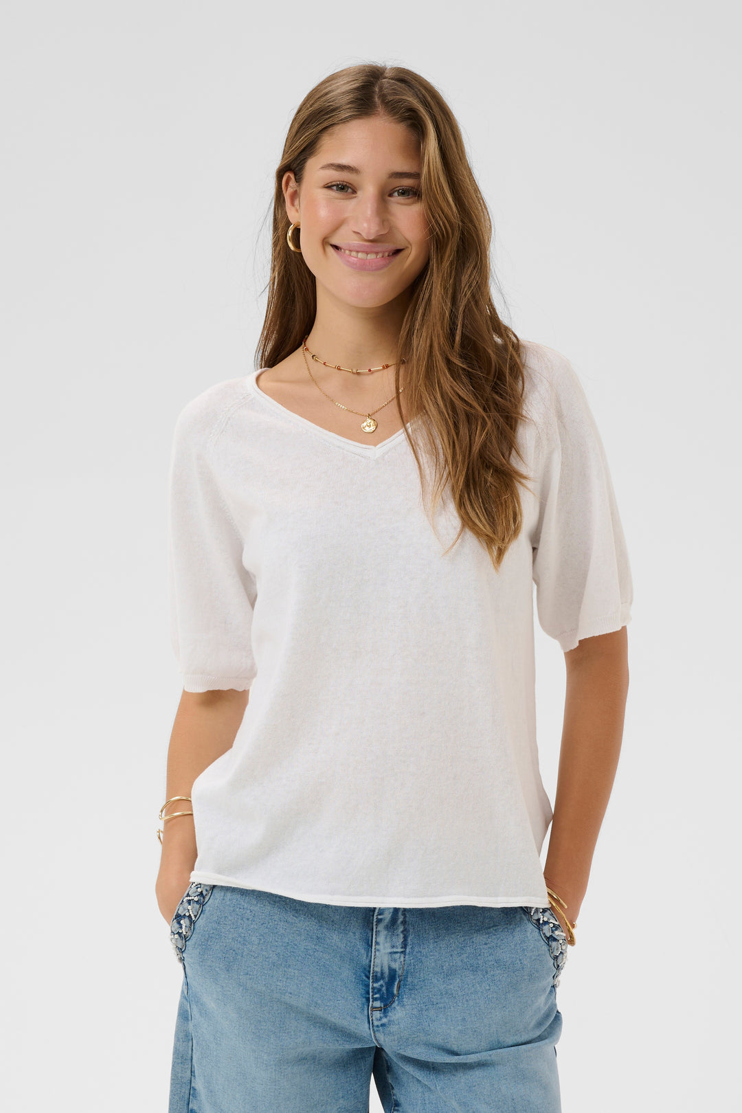 T-shirt Romane décontracté à encolure en V et manches courtes amples pour un look quotidien, porté par une femme souriante.