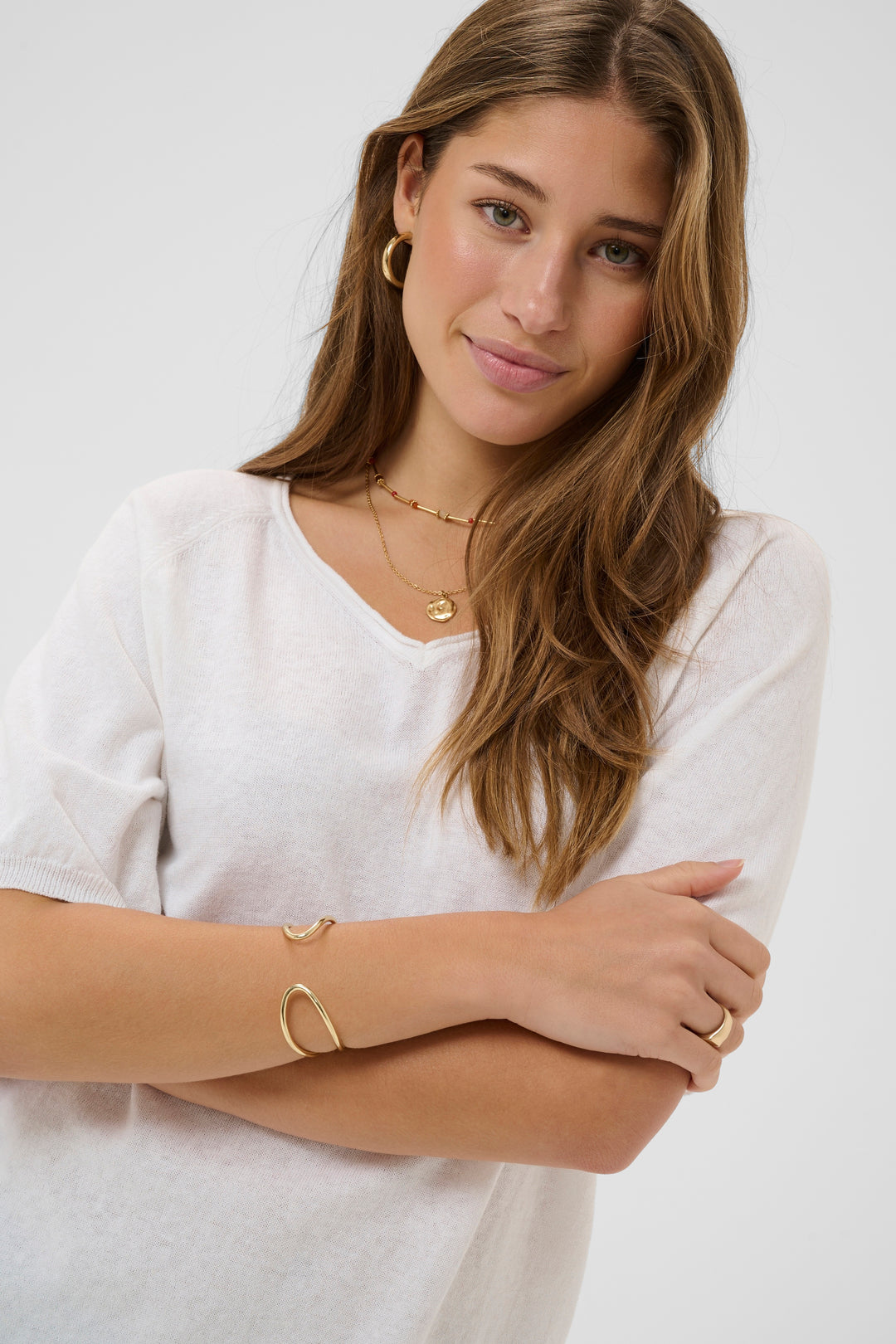 Femme portant le T-shirt Romane en blanc avec encolure en V et manches amples, style décontracté et féminin.