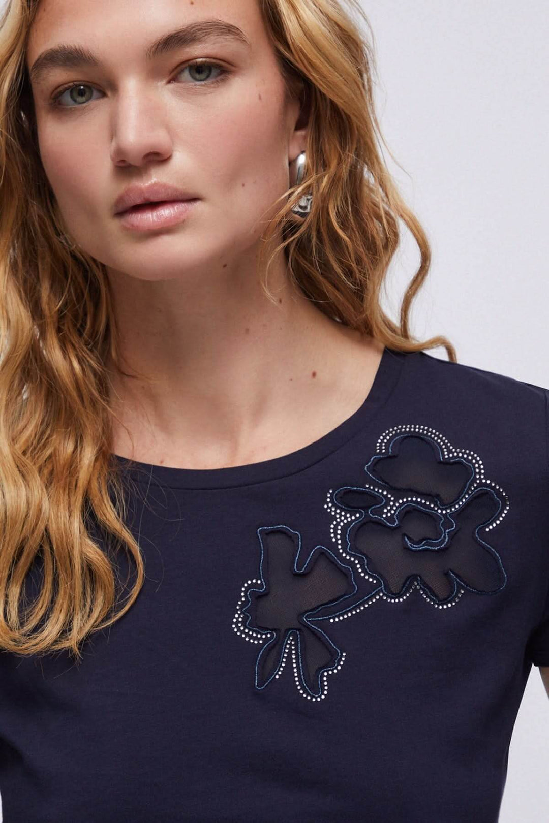 Femme portant un t-shirt avec appliqué floral décoratif sur l&