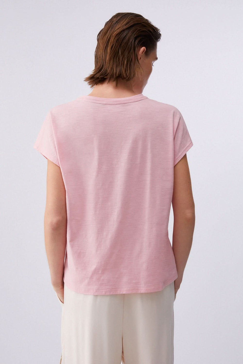 Vue de dos d'un T-shirt avec logo décoratif, tissu doux et confortable, manches courtes, couleur rose. Idéal pour une tenue quotidienne.